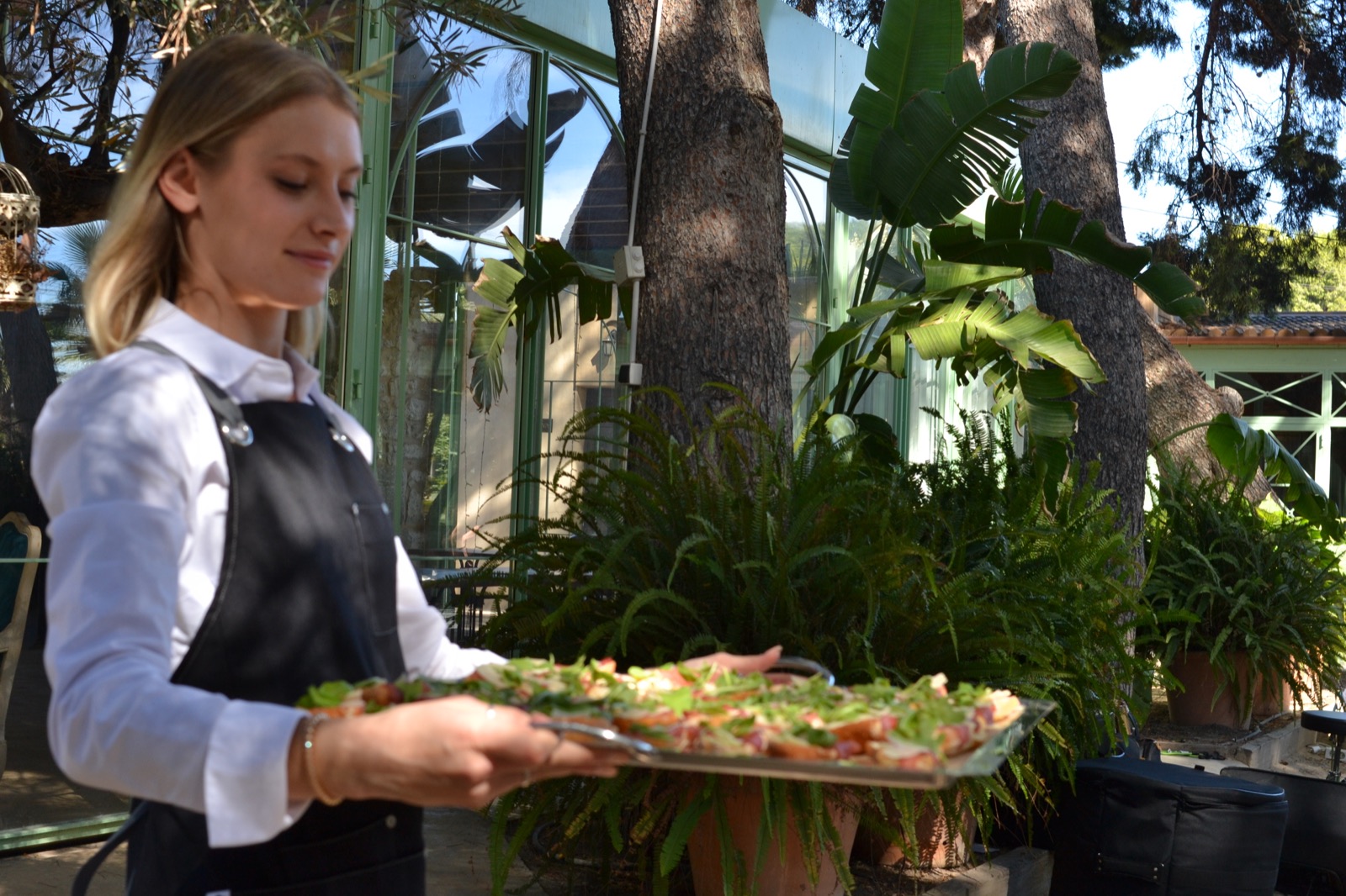 Camarera sirviendo una bandeja de aperitivos en jardín
